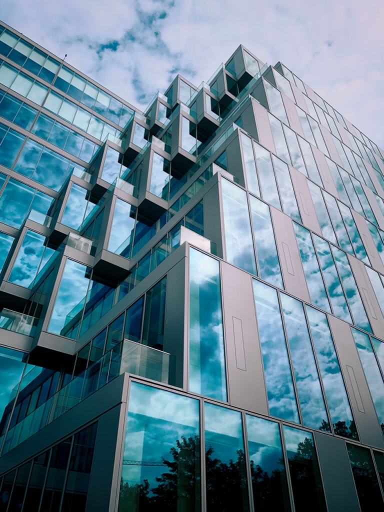 Glass building of stacked cube-shaped sections reflecting clouds