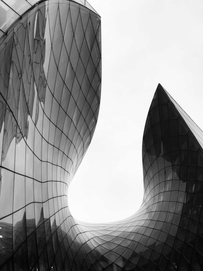 Black and white view of a curving glass building against a pale sky
